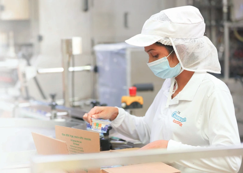 An employee checking a CIC Creamoo Yoghurt from production line